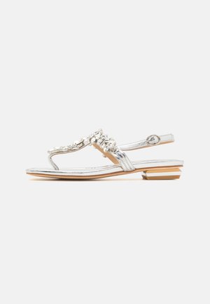 Silver metallic thong sandals featuring a decorative cluster of stones, flat sole, and adjustable ankle strap with a round buckle.