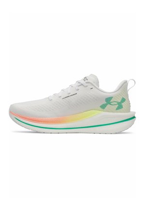 Witte Under Armour hardloopschoen met veters, een gele-oranje verloopzool en een groen logo op de hiel en de rand van de zool.