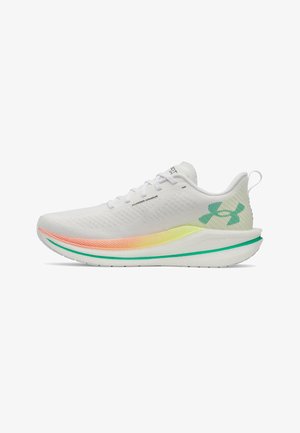 Chaussure de course Under Armour blanche avec lacets, semelle dégradée jaune-orange, et logo vert sur le talon et le bord de la semelle.