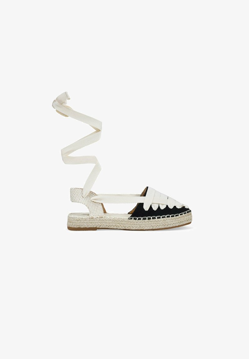 Schwarz-weiße Espadrilles mit gewebtem Jute-Absatz, flacher Sohle und überkreuzten Riemen; verfügen über ein strukturiertes, gemustertes Design auf der Vorderseite.