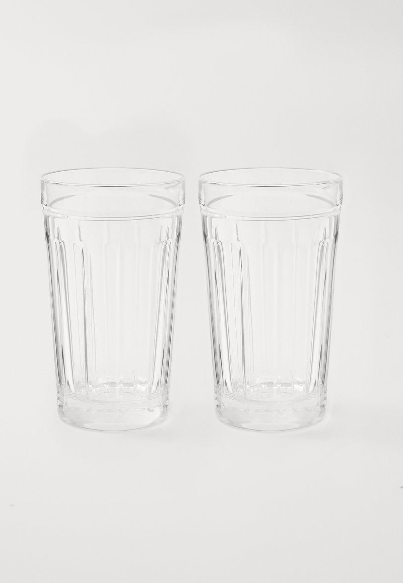 Διαφανή γυάλινα ποτήρια με κάθετη ριγωτή υφή, ελαφρώς κωνική μορφή και λείο χείλος. Δύο ποτήρια τοποθετημένα το ένα δίπλα στο άλλο.