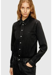 Camicia di jeans nera con bottoni e collo, caratterizzata da bottoni metallici e un logo sottile sul petto sinistro. Maniche lunghe e vestibilità sagomata.