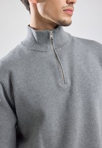 Gray pullover sweater with a high collar and half-zip closure. Soft texture, ribbed cuffs, and smooth material with a regular fit.