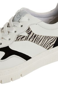 Hvide lædersneakers med zebrastribet suedepanel, sorte detaljer, tekstureret gummisål og snørebåndsdesign med robuste øjer.