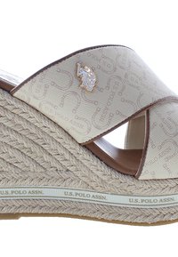 Sandalo con zeppa in espadrille, tomaia in tessuto beige con un motivo a logo stampato, cinturini incrociati, suola in juta intrecciata e dettagli in pelle marrone.