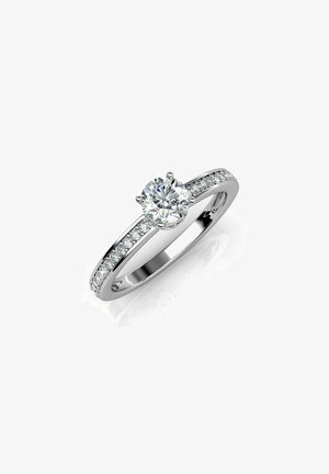 Bague en platine avec un diamant central rond et de plus petits diamants sertis le long de l'anneau. Fini poli, design élégant et éclat brillant.
