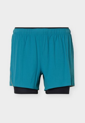 Πράσινα-μπλε αθλητικά σορτς με ενσωματωμένη μαύρη εσωτερική στρώση συμπίεσης και ελαστική μέση, εμφανιζόμενα σε απλό λευκό φόντο.