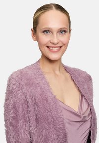 Cardigan en lavande flou porté sur un haut drapé de lavande. Le cardigan présente une texture douce et un design à l'avant ouvert, créant un look superposé.