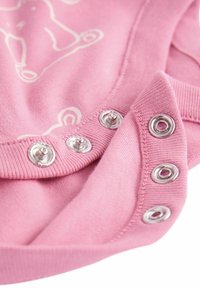 Rosa Baumwollkleidung mit silbernen Druckknöpfen entlang des Ausschnitts, aus einem glatten, weichen Material und mit illustriertem Designdetail.