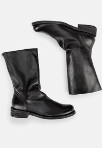 Bottes noires en cuir montantes avec une texture lisse, bout arrondi et talon empilable. Présentent un design décontracté et une fermeture éclair sur le côté.