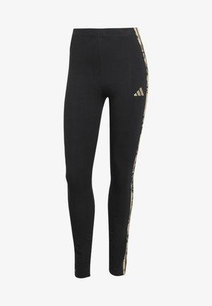 Leggings aderenti neri con strisce laterali beige a motivo e piccolo logo Adidas beige sulla parte superiore della coscia.