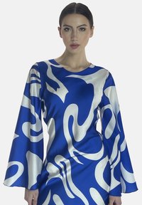 Vestito di raso blu con motivi astratti bianchi, maniche a campana lunghe e scollatura rotonda. Texture liscia, forma aderente alla vita.