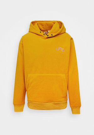 Sudadera con capucha amarilla mostaza con bolsillo frontal, pequeño logo rojo y blanco "LEVI'S" en el pecho, y capucha ajustable con botones a presión negros.