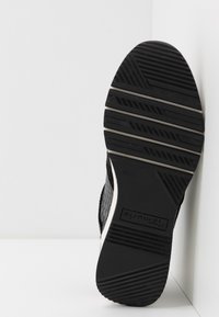 Schwarze Sneakersohle aus strukturiertem Gummi mit einem gemusterten Grip und einer weißen Akzentlinie. Das Markenlogo "Tematis" ist in der Nähe der Ferse sichtbar. Größe 37.