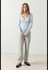 Lyseblå langermet topp med blonder, grå sweatpants og svarte slip-on sko. Glatt stoff, tettsittende design og elastiske mansjetter.