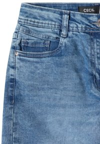 Jean en denim bleu clair en gros plan montrant la poche avant, la boucle de ceinture, le bouton et l'étiquette de marque noire "CECIL" sur la ceinture.