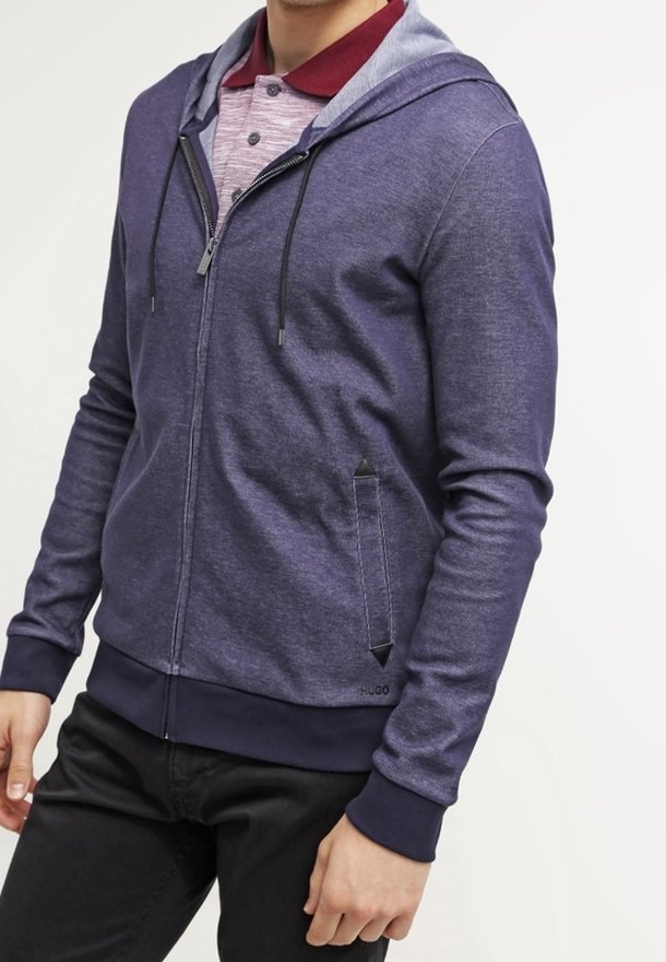 Felpa con zip di colore blu navy, con cappuccio foderato grigio, caratterizzata da un tessuto testurizzato, tasche frontali con accenti neri e polsini a costine.
