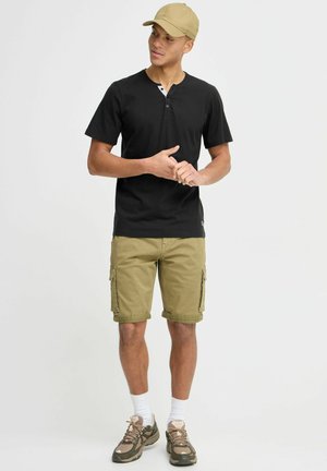 Sort svart henley skjorte med kort erme og to knapper, kombinert med beige cargo shorts med sidelommer og oppbrettede ermer.