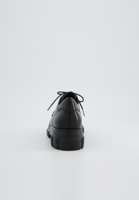 Scarpa in pelle nera con punta arrotondata, suola spessa e testurizzata, e lacci piatti. Presenta cuciture sottili e un piccolo logo sul tallone.