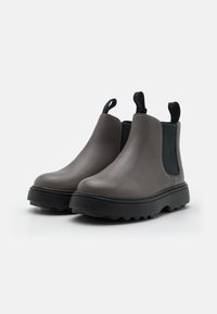 Botas Chelsea de cuero gris con paneles laterales elásticos, suela de goma negra gruesa y tiradores para ponerlas fácilmente. Diseño texturizado con un acabado suave.