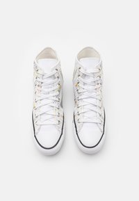 Para białych sneakersów typu high-top z kolorowymi, abstrakcyjnymi wzorami linii, białymi sznurowadłami i czarnymi wykończeniami, widzianych z góry na białym tle.