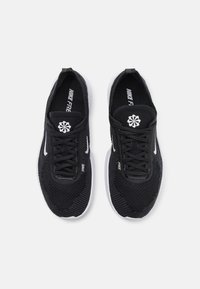 Crne atletske tenisice s mrežastim gornjim dijelom, bijelim detaljima, teksturiranim elementima i ravnim vezicama. Imaju Nike Free oznaku na jeziku i sa strane.