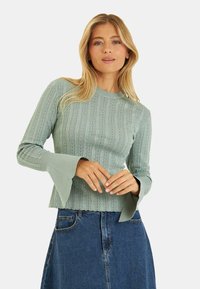 Mintgrüner, gerippter Pullover mit langen Ärmeln und ausgestellten Manschetten, der ein strukturiertes Muster und einen Rundhalsausschnitt aufweist.