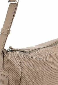 Borsa a spalla beige con un motivo testurizzato a squame, una zip superiore liscia e una tracolla piatta con hardware regolabile.