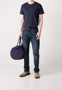 Marine bomulds T-shirt, mørkeblå denim jeans, beige ruskind ankel støvler og en rund marine canvas taske med dobbelte hanke.