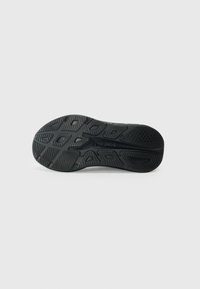 Semelle de chaussure de sport noire avec du caoutchouc texturé, présentant des motifs de traction multidirectionnels et un logo au centre.