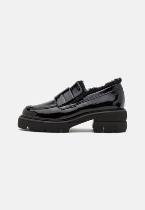 Mocassin en cuir verni noir avec semelle crantée épaisse et doublure en fourrure noire douce autour du col, présenté de profil sur un fond blanc.