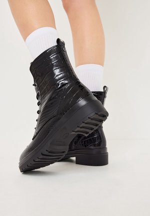 Bottes de cheville en simili cuir noir avec une texture crocodile, un design à lacets et une semelle en caoutchouc robuste avec des rainures de traction.