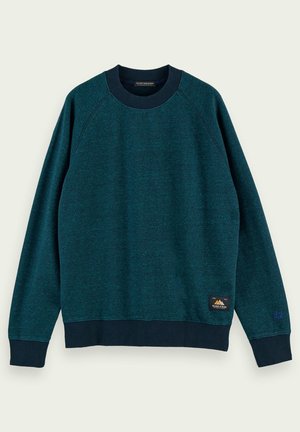 Sweatshirt à col rond bleu sarcelle foncé avec poignets, col et ourlet côtelés bleu marine, avec une petite étiquette de marque près du bas et une broderie discrète sur la manche.