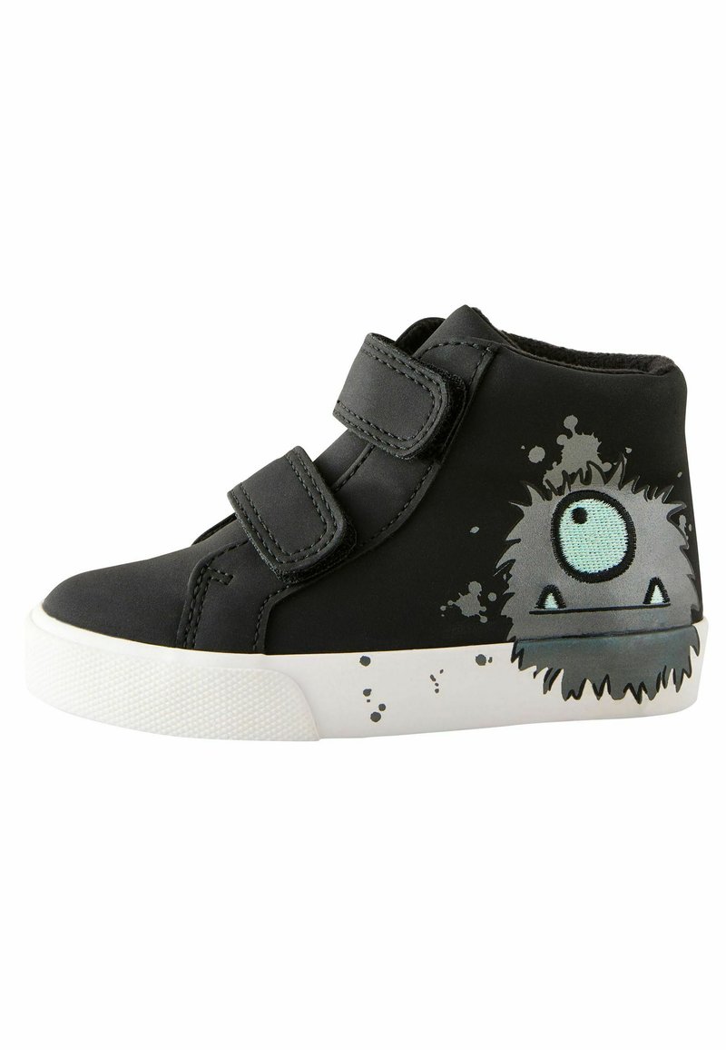 Sneaker nera a metà altezza con due strap in velcro, caratterizzata da una grafica di un mostro e un design a spruzzi sulla suola bianca. Materiale in gomma morbida, finitura texturizzata.