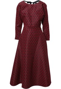 Robe à motif rouge et noir avec des manches longues, taille cintrée et jupe évasée. Détail de nœud dans le dos qui ajoute un accent notable.