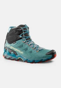 Scarponcino da trekking impermeabile con una tomaia sintetica turchese e nera, suola in gomma, tacco rialzato e lacci e dettagli multicolori.