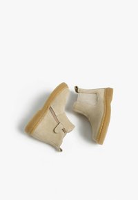 Beige Wildleder-Stiefeletten mit einem seitlichen Reißverschluss, strukturiertem Obermaterial, runden Zehen und hellbraunen Gummisohlen.