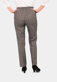 Geruite broeken met een elastische tailleband, met een bruin en grijs ruitpatroon. De stof lijkt soepel en gestructureerd.