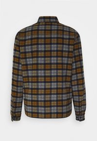 Plaid shirt in gray, navy, and mustard yellow tones. Designed with a collared neck, long sleeves, and buttoned cuffs, made from flannel material.