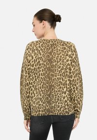Maglione con stampa leopardata in tonalità beige e marrone, dotato di scollo rotondo, maniche lunghe e vestibilità ampia. Dettaglio particolare sulla schiena.