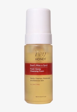 Genomskinlig plastflaska med ett vitt pumplock, fylld med bärnstensfärgad rengöringsskum, med röda och svarta textetiketter.