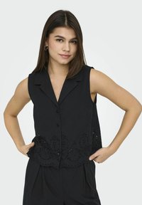 Blusa nera senza maniche con collare, apertura frontale con bottoni e dettagli ricamati a occhiello lungo l'orlo. Tessuto liscio e vestibilità rilassata.