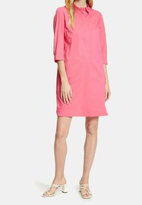 Abito camicia in cotone rosa con colletto, maniche a tre quarti e vestibilità dritta, abbinato a sandali bianchi con tacco a blocco.