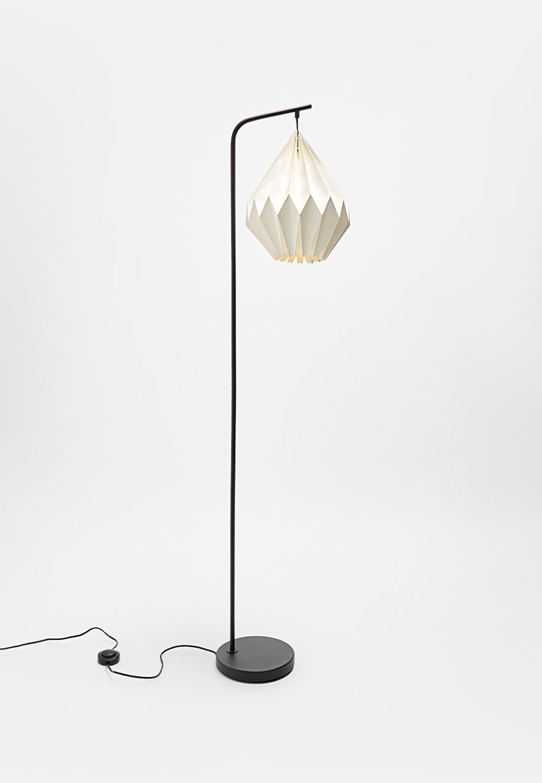 Stehlampe mit einem schlanken schwarzen Metallständer und runder Basis. Verfügt über einen geometrischen weißen Stoffschirm mit einem strukturierten, plissierten Design.