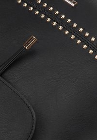 Sac à main en cuir noir avec des accents de clous dorés et une fermeture zippée. Comprend une surface texturée et une languette décorative.