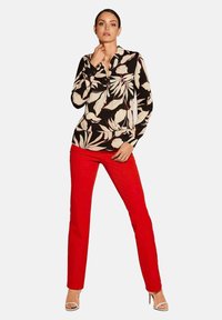 Long-sleeve blouse with a black and cream floral pattern, paired with fitted red pants and nude strappy heels.