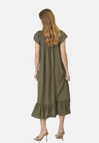 Vestido verde oliva, a la altura de la rodilla, con mangas cortas, bodice fruncido y dobladillo acampanado. Hecho de una tela suave y fluida, adecuada para el clima cálido.