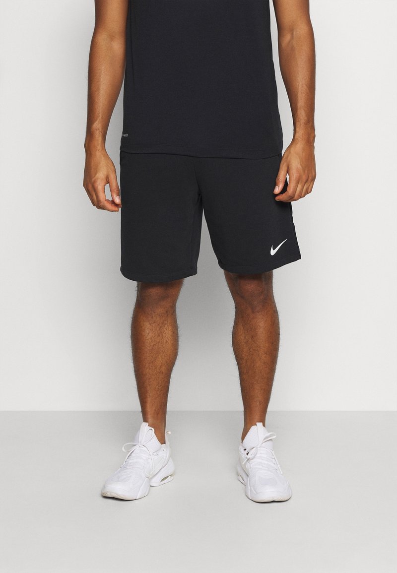 Svarta sportshorts med en vit Nike-logotyp, tillverkade av mjukt tyg, i kombination med en svart t-shirt och vita sneakers, med en klassisk design.