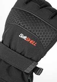 Black softshell glove with hexagonal texture, featuring adjustable strap and logo in red. Reinforced stitching visible, designed for insulation.