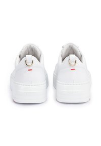 White leather sneakers with a textured finish, featuring a gold loop at the heel, red accent, and raised white sole with branding.